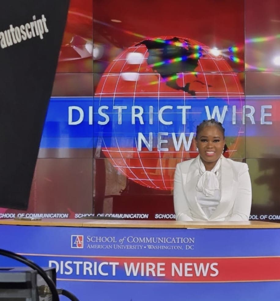 Tayo Ojewunmi-Ojo seated at a broadcast news desk